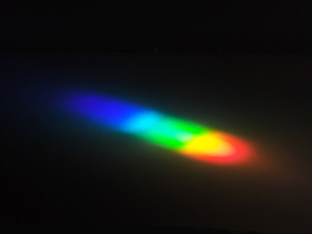 a rainbow formed by light refracting through an alum crystal