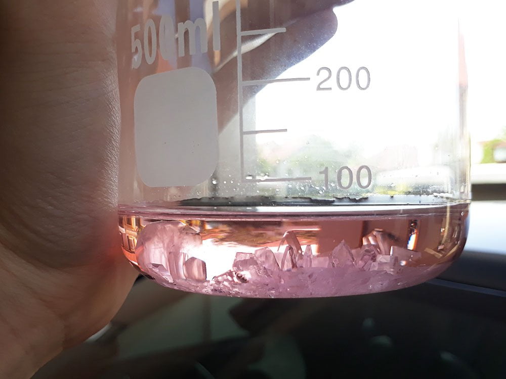 Pink manganese sulfate crystals in a beaker.