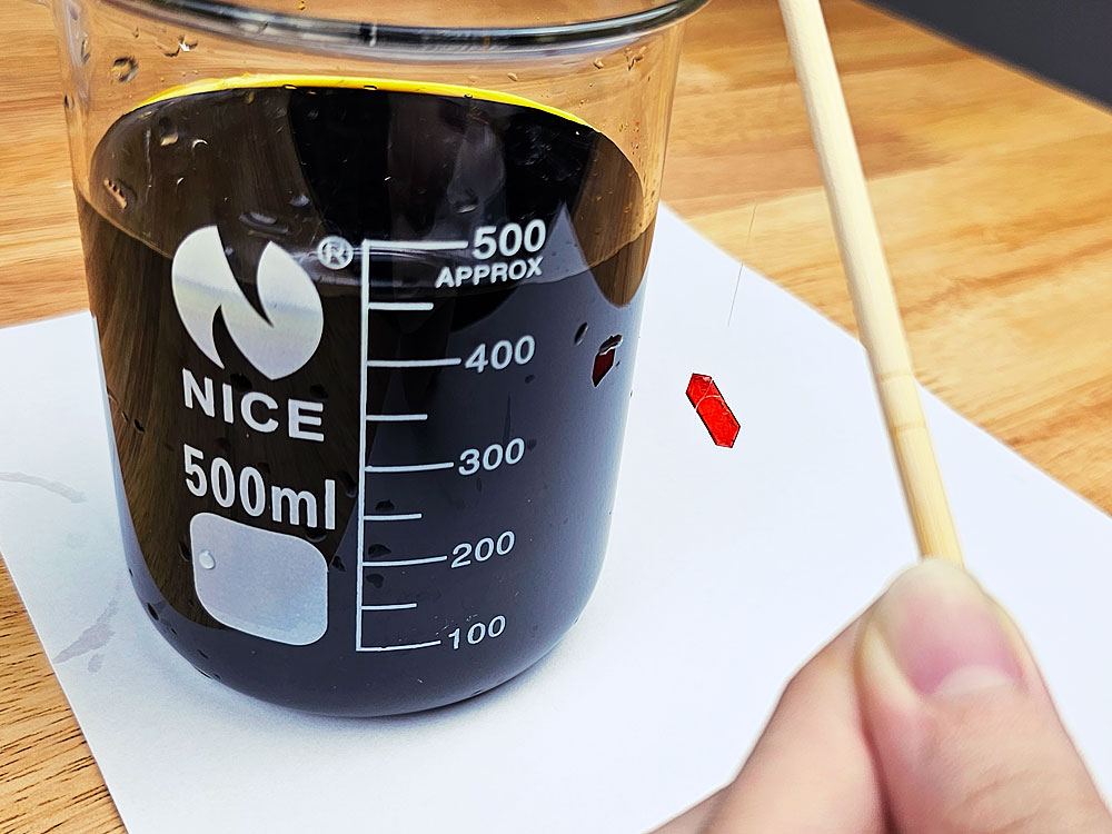 A potassium ferricyanide crystal, attached to a fishing line on a stick.